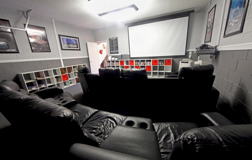 Grey home cinema with projector screen and large black leather theater recliners