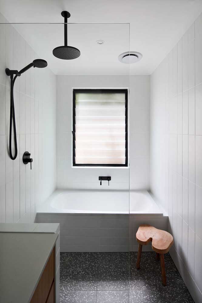 A charming wooden stool to complement the look of the small bathroom with a bathtub.